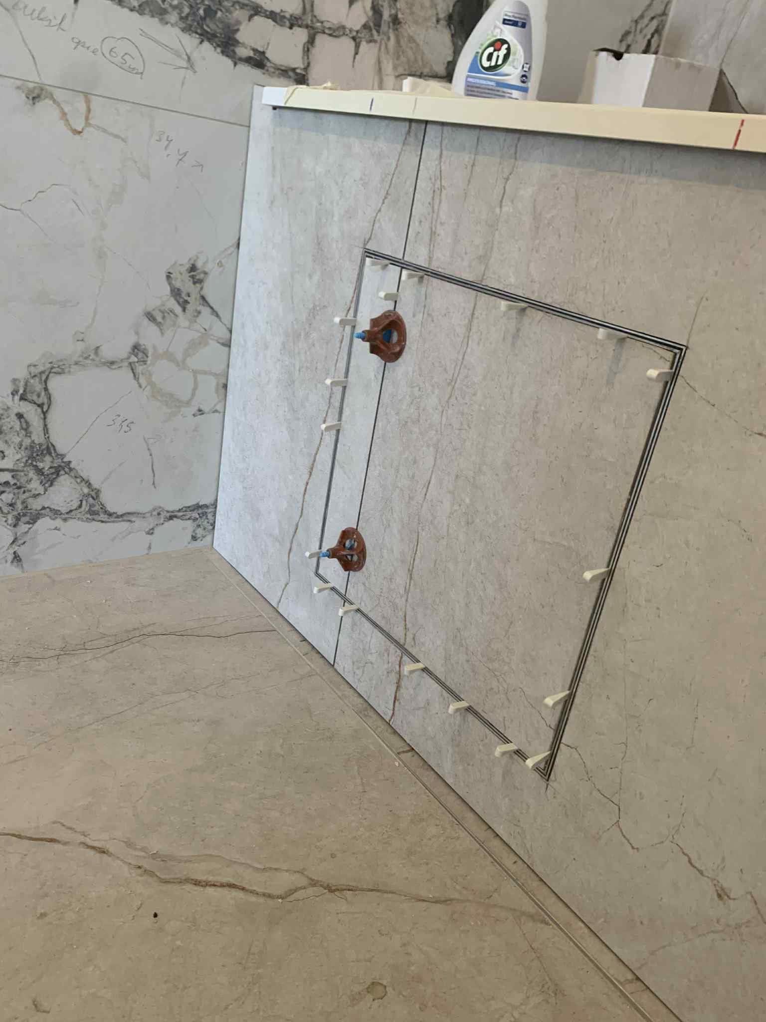 Revizinių durelių įrengimas marmuro imitacijos plytelių sienoje